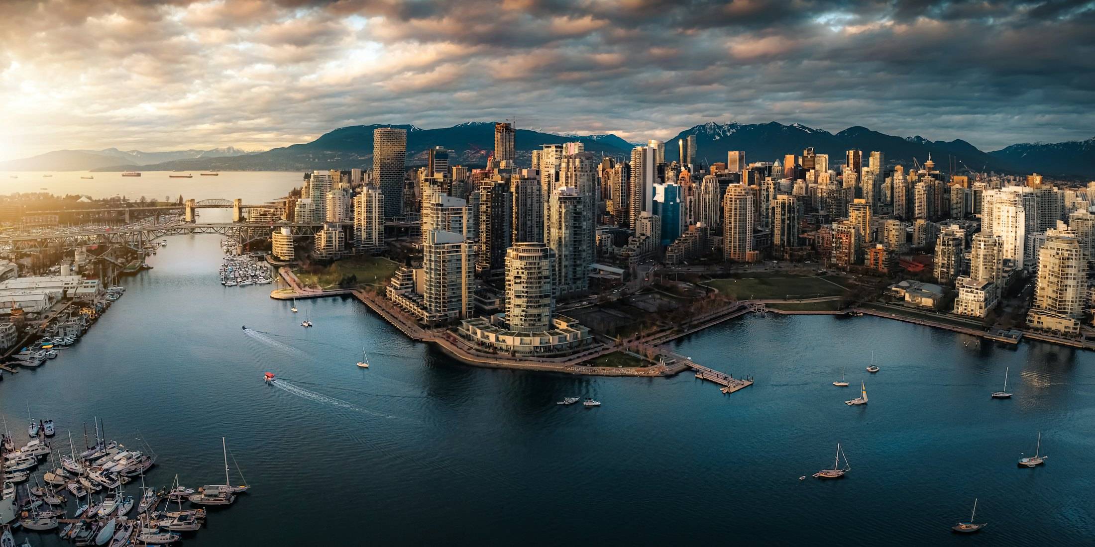 Downtown Vancouver from the air at golden hour, surrounded by water with mountains behind